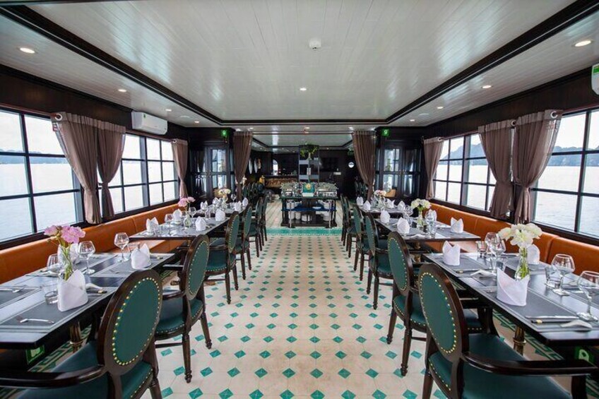 Comedor con mesas dispuestas para el servicio, sillas tapizadas en verde y piso estampado. 2