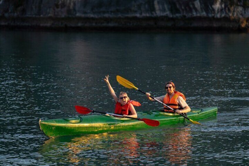 Dos personas kayakendo en aguas tranquilas con acantilados rocosos al fondo. 1