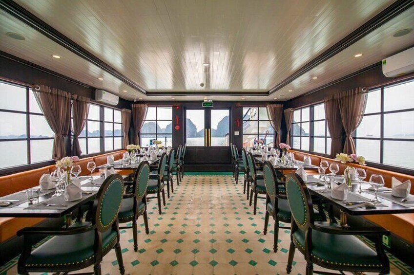 Comedor con mesas dispuestas para una comida, ventanas amplias y vista al mar. 4
