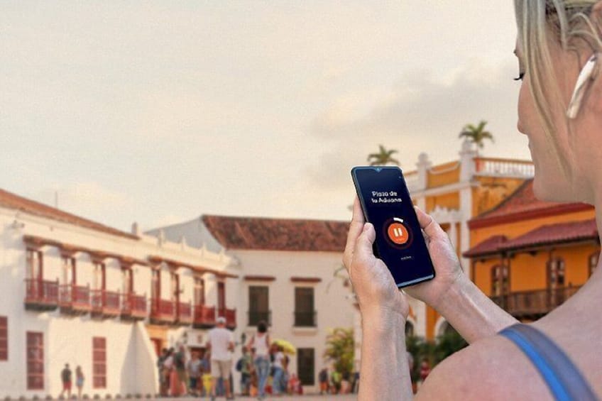 A person using a smartphone with a map application, standing in front of a building with balconies and a red roof. 4