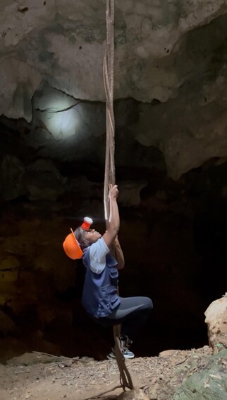 A person climbing a rope in a cave. 2
