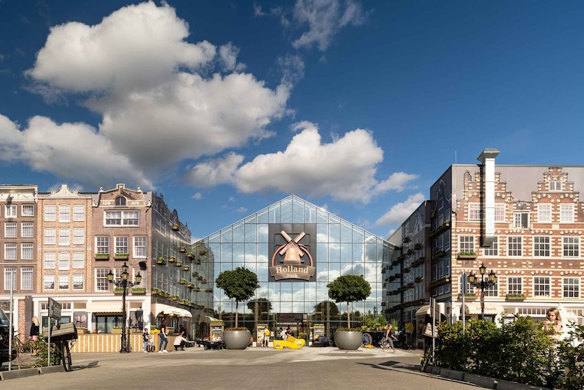 A modern glass building with a sign reading 'Holland Park' in the center of a city street. 2