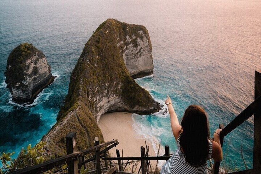 Eine Person zeigt auf eine große Felsformation am Meer. 2