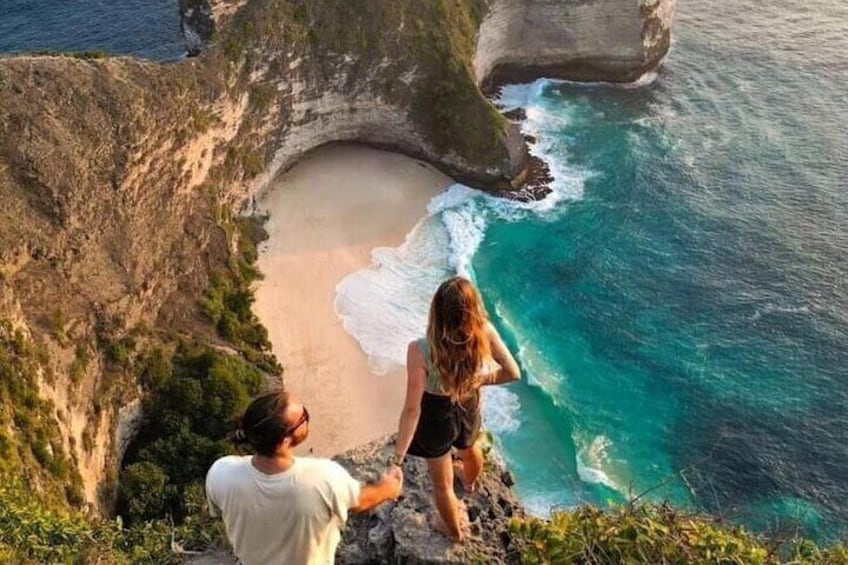 Ein Paar blickt auf eine Küstenklippe mit Strand und türkisfarbenem Wasser. 1