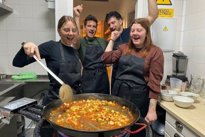 Vier Personen kochen in einer Küche und rühren in einem großen Topf. 2