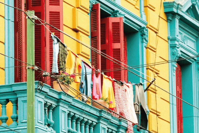 A colorful building with red and yellow shutters and clothes hanging on a line. 1