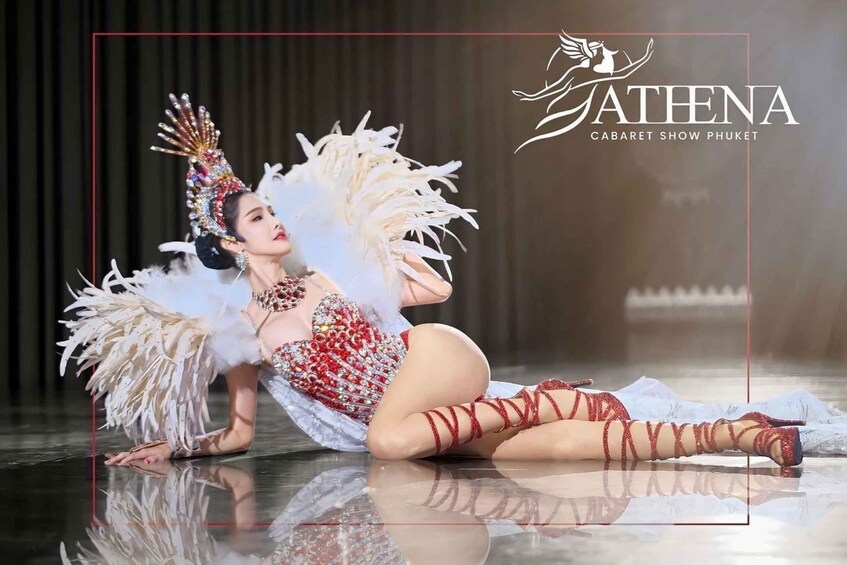 A performer in a white feathered costume with red accents, posing on a reflective floor. 2