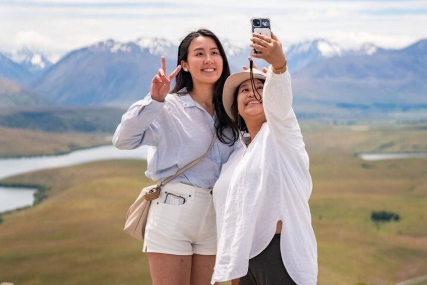 Deux personnes prenant un autoportrait avec un paysage montagneux en arrière-plan. 1