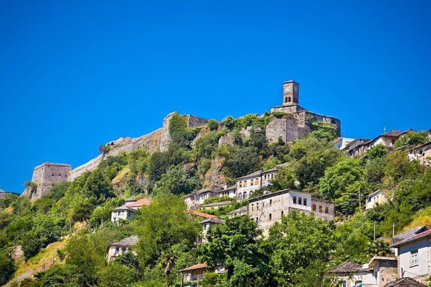 Un borgo collinare con edifici storici in pietra e una torre imponente. 1