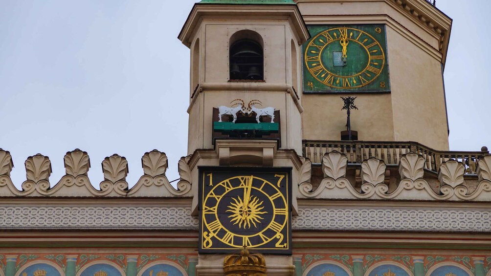 A building with ornate architectural details, including a clock tower with a large clock face and decorative elements like a sun emblem and animal sculptures. 4