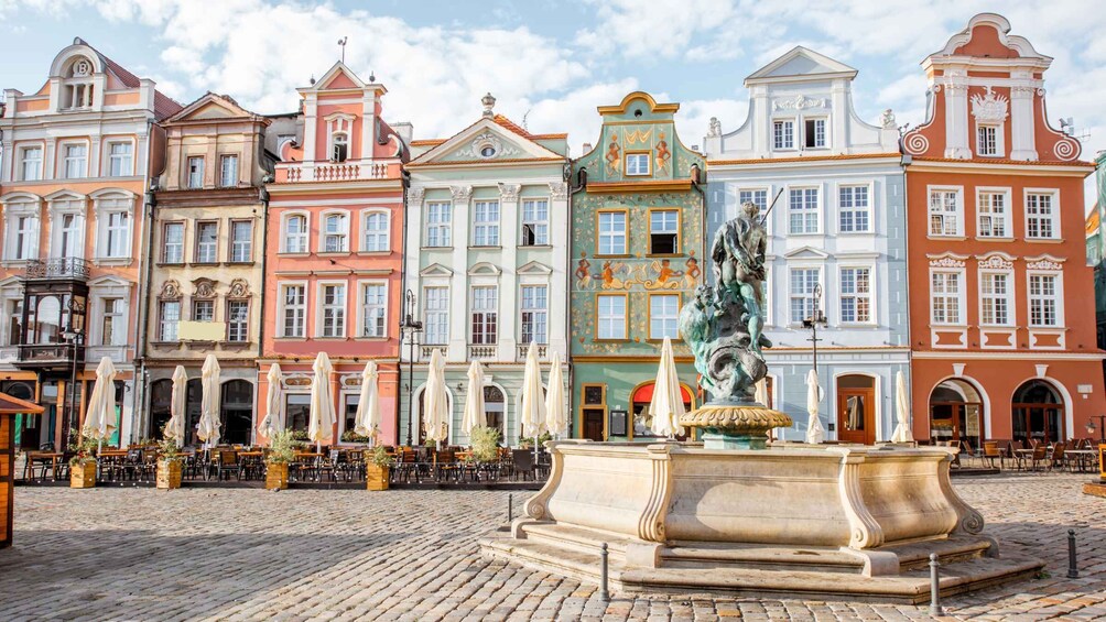 A cobblestone square with colorful historic buildings and a statue fountain. 5