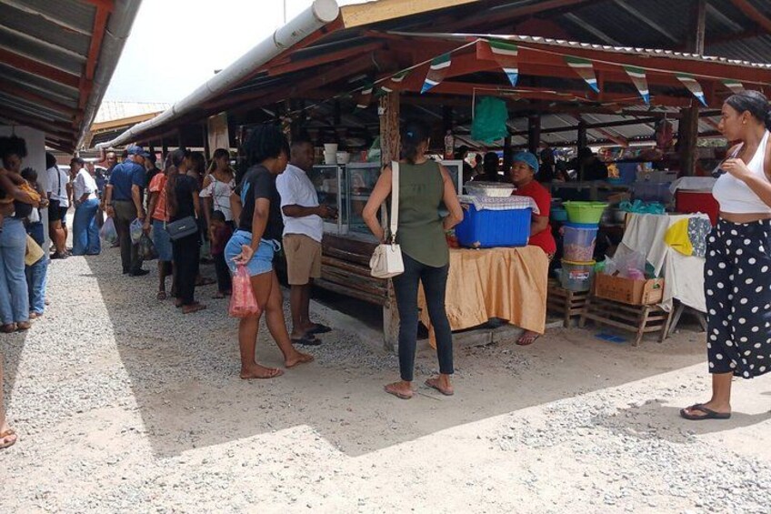 A market with people shopping and vendors selling goods under a covered area. 2