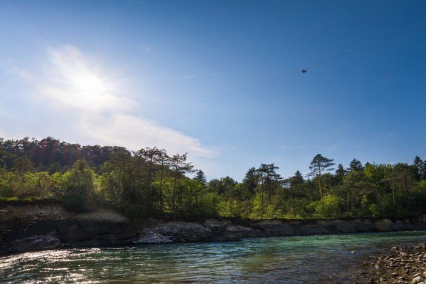 Un fiume con acque cristalline, circondato da una fitta foresta e un elicottero nel cielo. 3