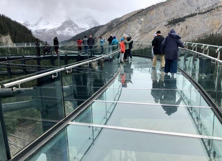 A glass bridge with people walking on it, overlooking a mountainous landscape. 3