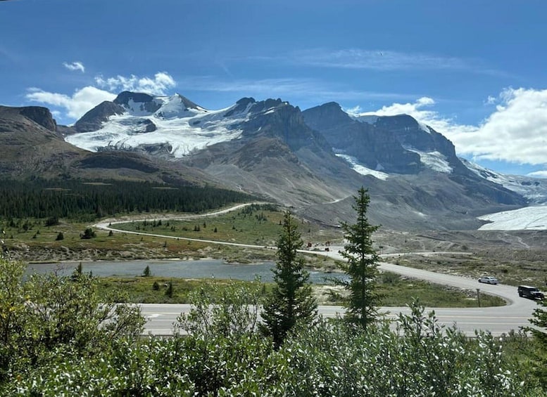 A mountain landscape with a road, a lake, and a glacier. 5