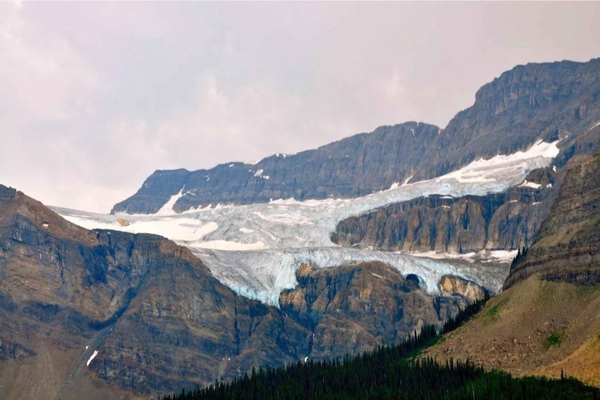 A glacier in a mountainous landscape with steep cliffs and sparse vegetation. 4