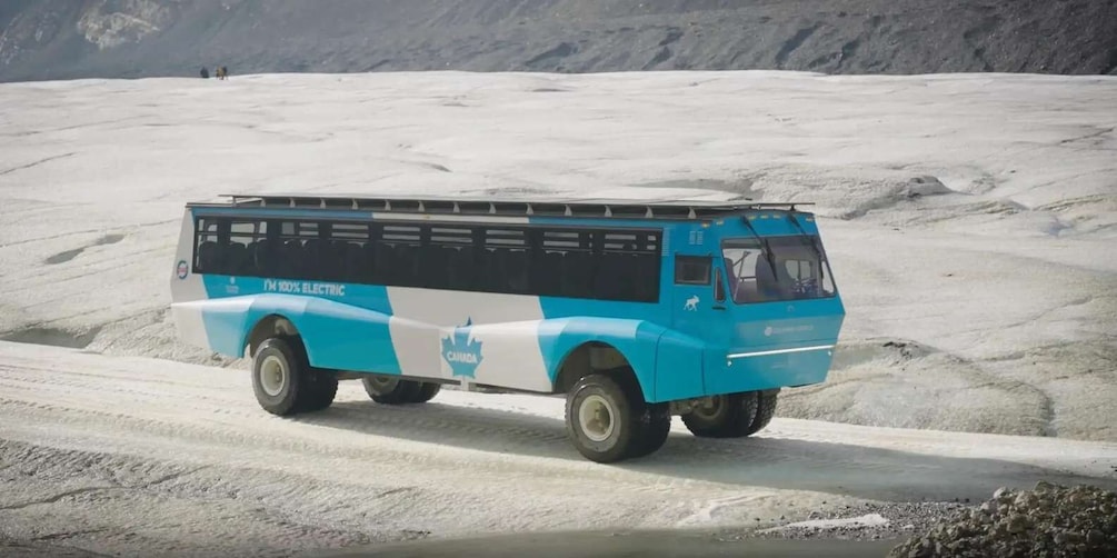 A blue and white electric bus on a snowy road. 1
