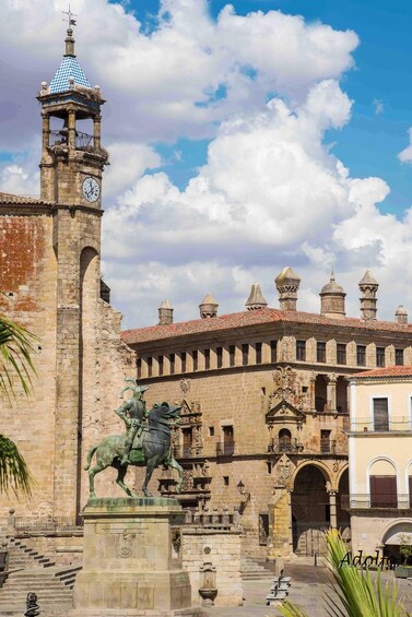 A historic building with a clock tower and a statue of a knight on horseback. 1