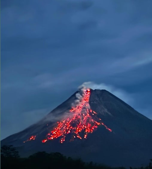 A volcano with lava flowing down its side at night. 2