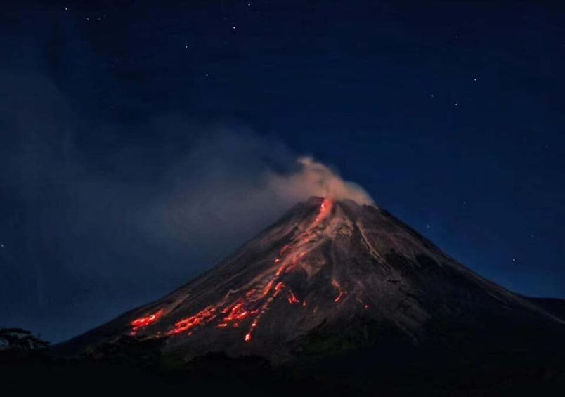 A volcano at night with glowing lava flows and smoke. 3