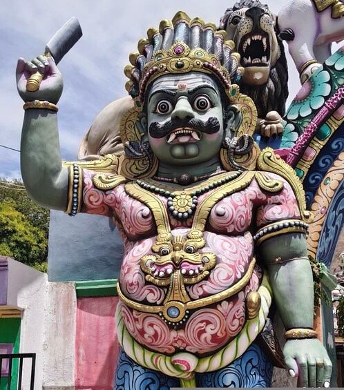 A colorful statue with intricate designs and a prominent figure holding a scroll. 1