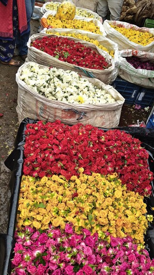 A flower market with large sacks of red, yellow, and pink flowers. 5