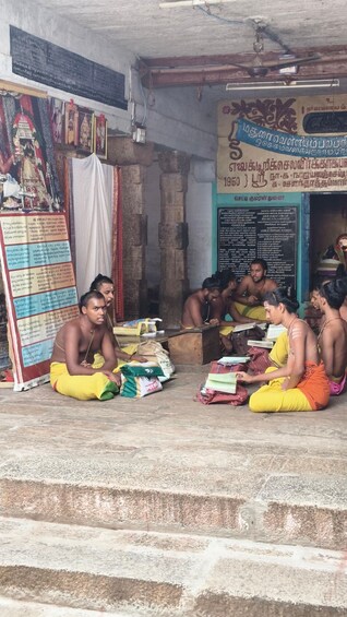 A group of men sitting on steps in a temple, surrounded by religious icons and scriptures. 2