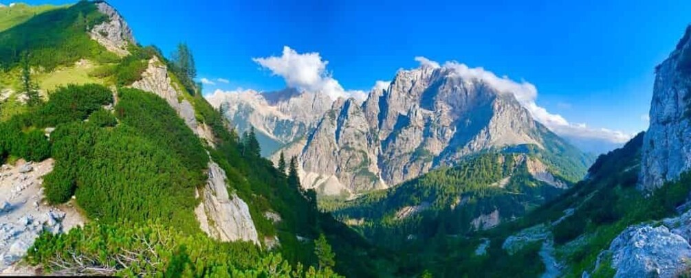 A mountain landscape with a prominent peak, dense forest, and a clear blue sky. 5