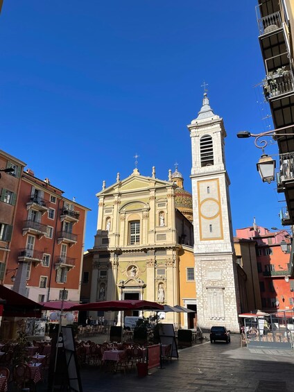 A historic building with a clock tower, surrounded by cafes and outdoor seating. 3