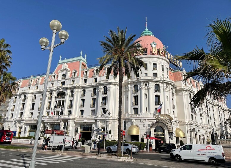 A large, ornate building with a pink dome and white facade, surrounded by palm trees and street lamps. 1
