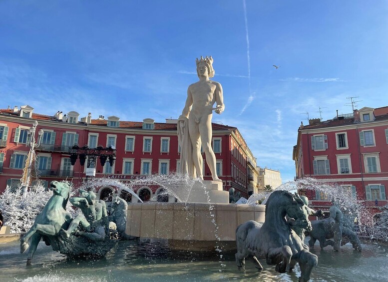 A statue of a man with a crown in a fountain surrounded by horses, with red buildings in the background. 4