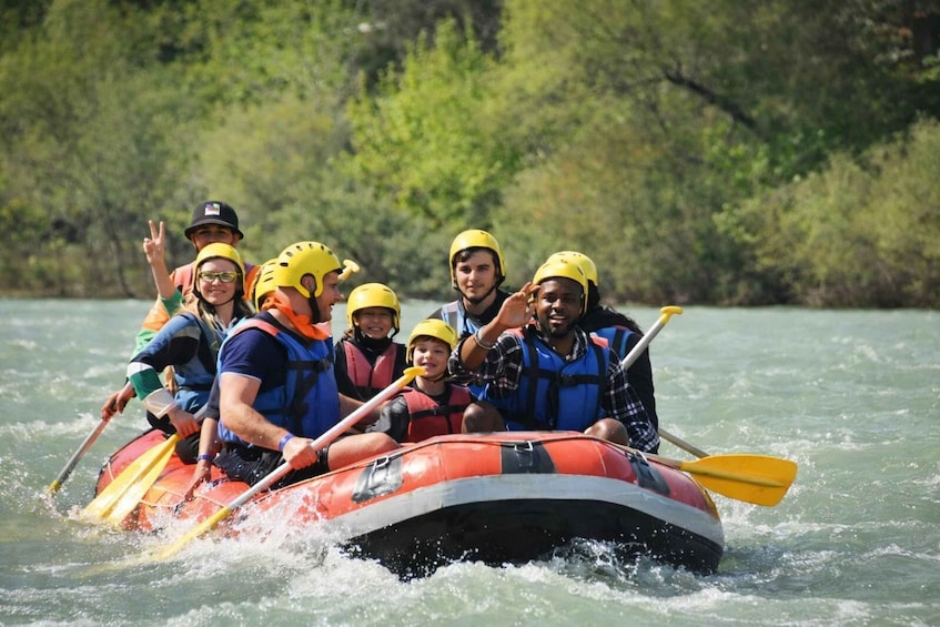 A group of people in a red and orange inflatable raft on a river. 2