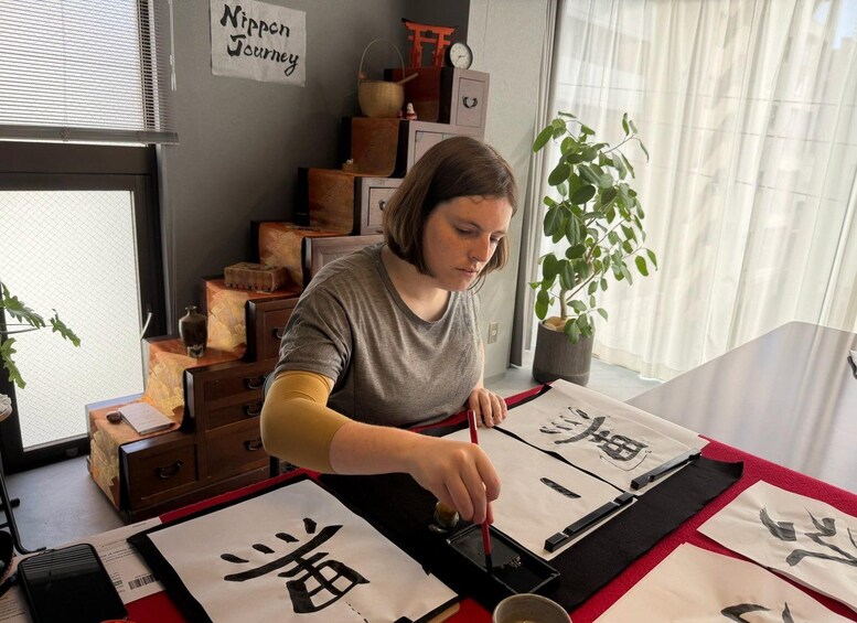 A person practicing calligraphy with ink and brushes on paper. 1