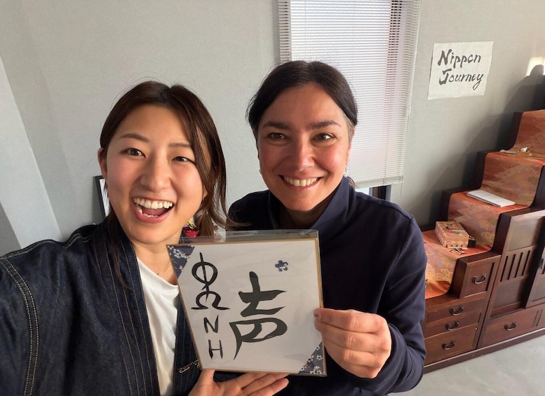 Two people holding a book with Japanese characters, a sign reading 'Nippon Journey,' and traditional Japanese furniture in the background. 1
