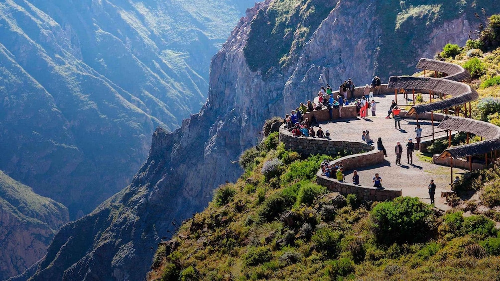 A group of people on a stone platform with a view of a canyon. 3