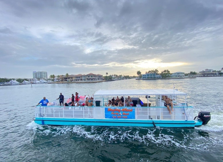 A party boat with people on board, moving on a body of water with buildings in the background. 5