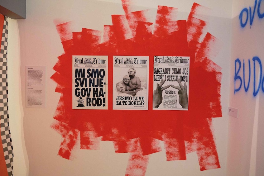 A wall with three newspaper clippings pinned to it, surrounded by red paint splatters. 2