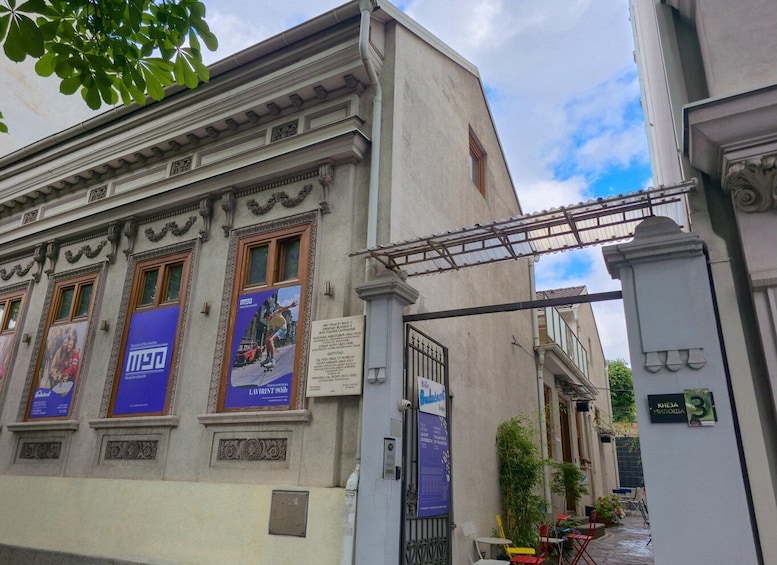 A building with classical architecture, posters on the windows, and a gated entrance. 3