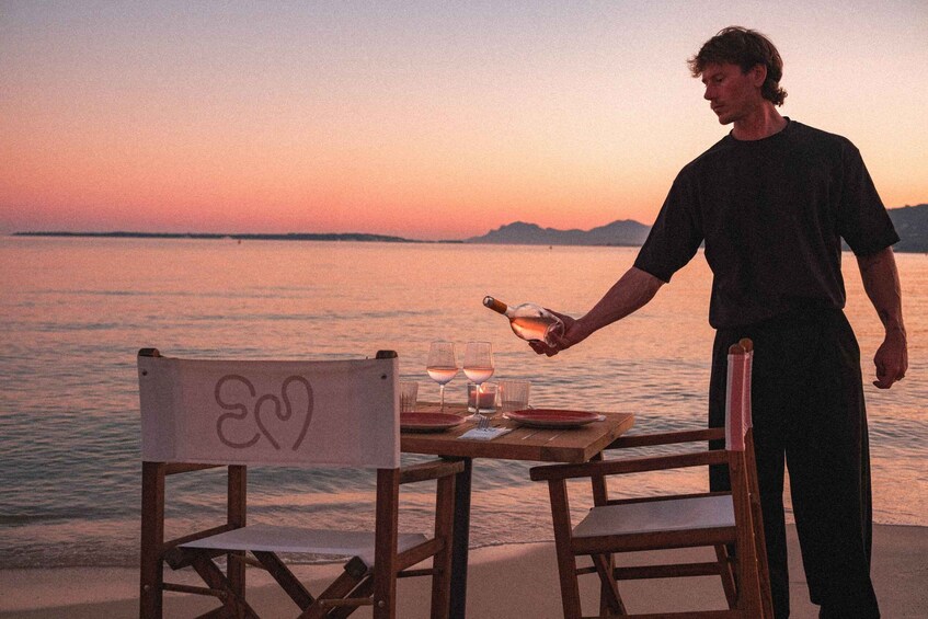 A person pouring champagne into glasses at a table by the water. 3
