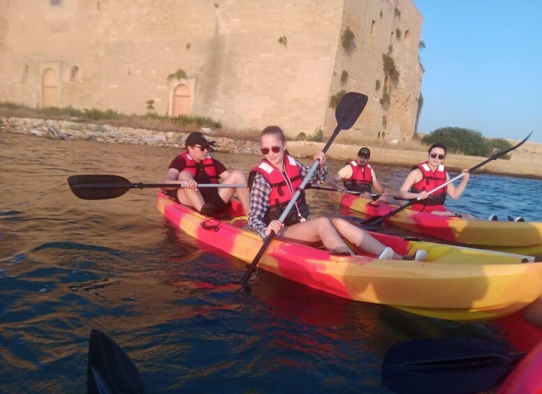 People kayaking on a river with a historic building in the background. 5