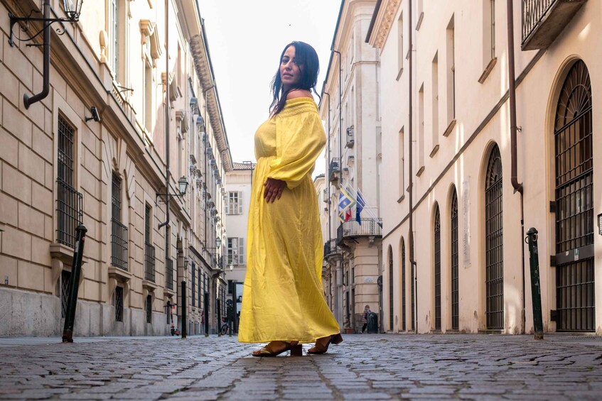 A woman in a yellow dress walking down a cobblestone street between buildings. 5