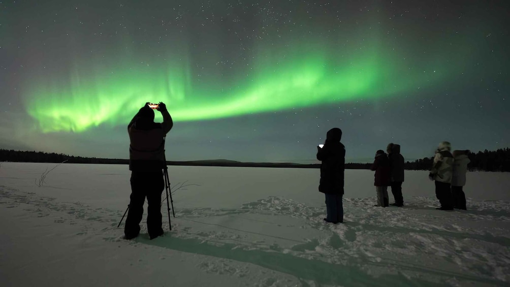 People observing the Northern Lights over a snowy landscape. 1