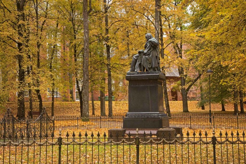 A statue in a park with autumn leaves. 5