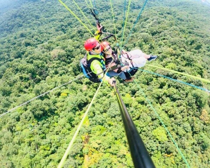 A person bungee jumping from a high point with a forested landscape below. 2