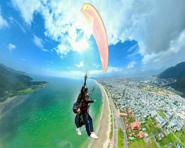 A person paragliding over a coastal area with a city in the background. 3