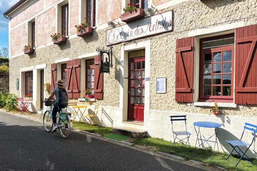 A stone building with red shutters and outdoor seating. 3