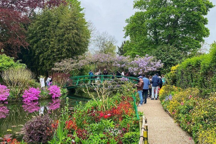 A garden with a pond, colorful flowers, and a green bridge. 5