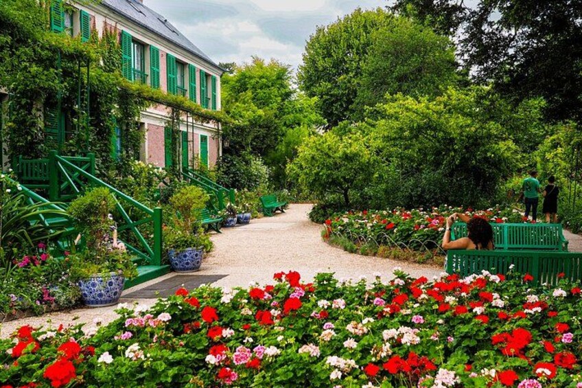 A garden with a pathway, green benches, and a building with green shutters. 5