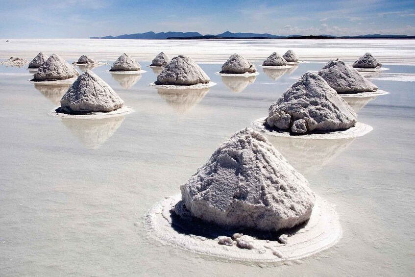 Salt formations in a flat landscape with mountains in the background. 2
