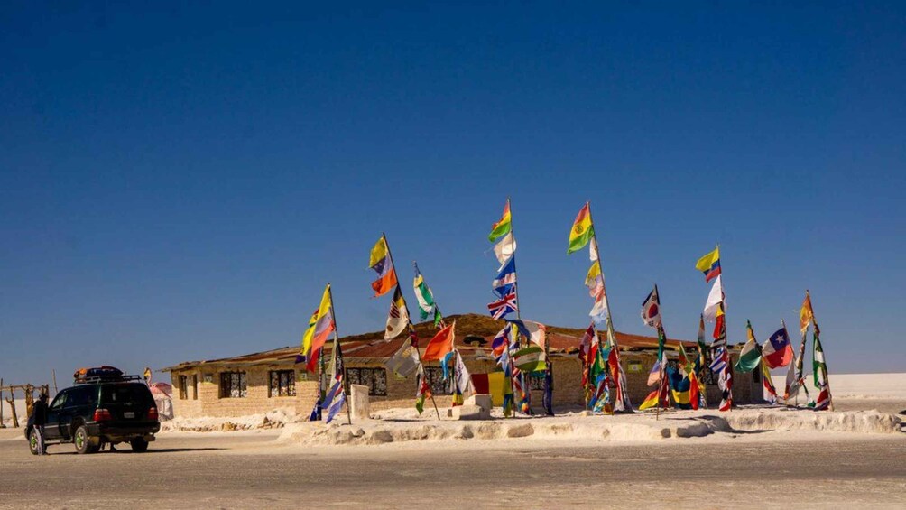 A desert landscape with a building and multiple flags in the foreground. 3
